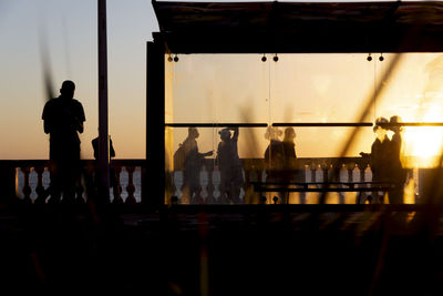 Silhouette at sunset of tree, bus stop and people walking on the edge of porto da barra.