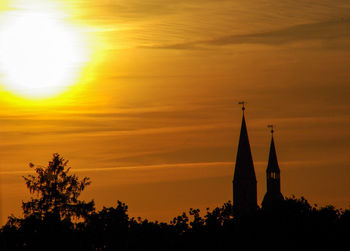 Silhouette trees against orange sky