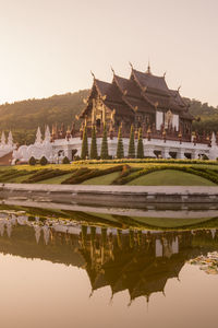 Temple by lake and buildings against sky