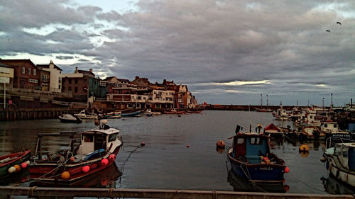 Sailboats in sea by town against sky