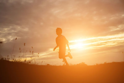 Silhouette man standing on beach against sky during sunset