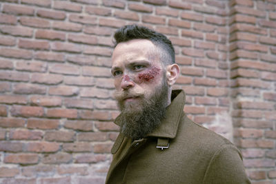 Portrait of man against brick wall