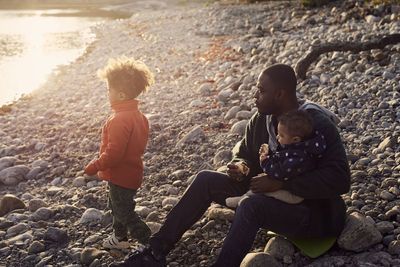 Father sitting with sons on rocks at beach