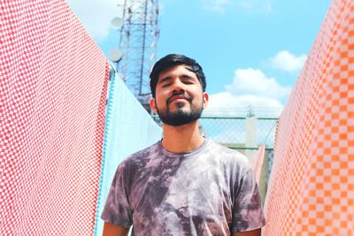 Man standing amidst clothesline against sky