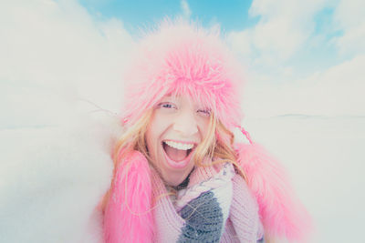 Portrait of young woman with pink eyes against sky