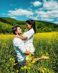 Side view of boyfriend carrying girlfriend amidst plants on field