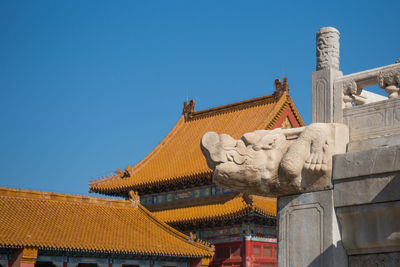 Low angle view of statue against building against clear blue sky