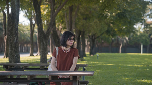 Side view of young woman sitting in park