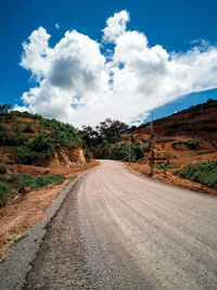 Dirt road amidst landscape against sky