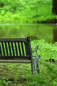 Empty bench on field by lake