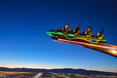 Low angle view of amusement park against clear blue sky