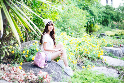 Portrait of beautiful young woman sitting by plants