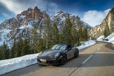 Car on road by snowcapped mountains against sky