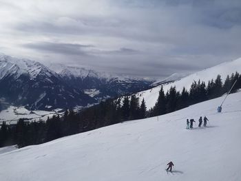 People skiing on snowcapped mountain against sky