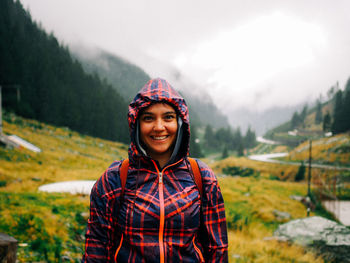 Portrait of smiling young woman standing against mountain