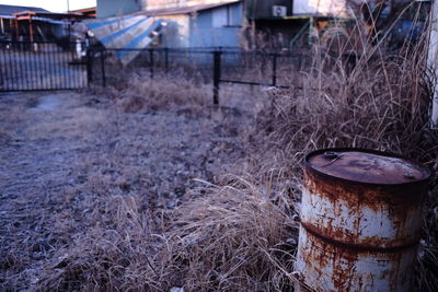 Rusty barrel on field against house