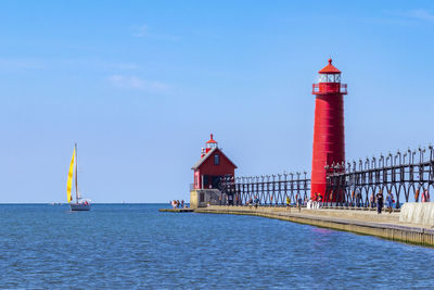 Lighthouse by sea against sky