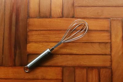 Directly above shot of wire whisk on parquet floor