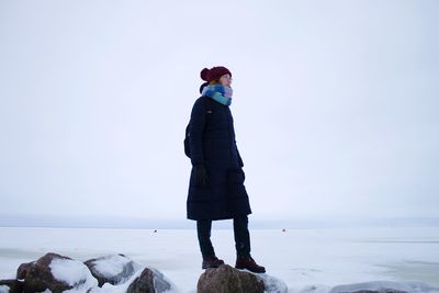 Man standing in sea against clear sky during winter