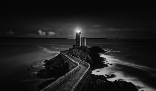 Illuminated lighthouse at beach during night