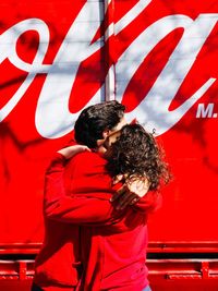 Rear view of couple standing with red umbrella