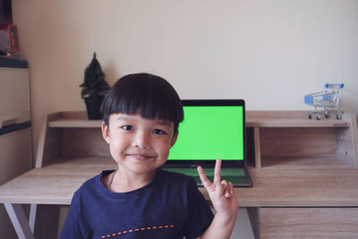 Portrait of smiling boy holding table at home