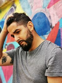 Portrait of young man looking away against wall