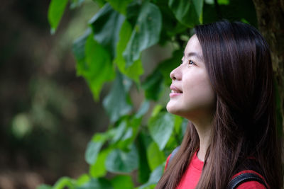 Side view of young woman against trees