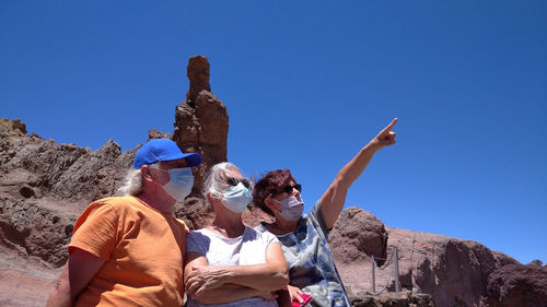 Low angle view of people against clear blue sky