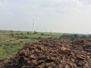 Wind turbines on field against sky