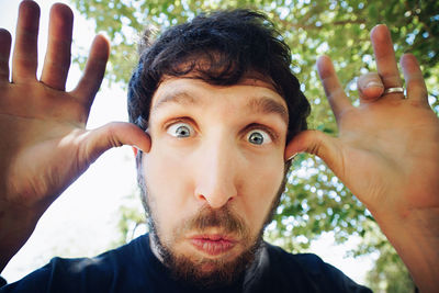 Close-up portrait of man gesturing against branches