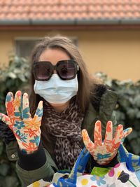 Portrait of woman wearing sunglasses and colorful gloves