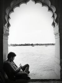 Rear view of woman sitting on bridge