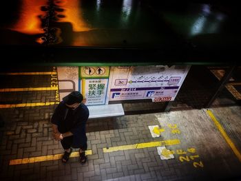 Rear view of man standing on illuminated street
