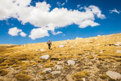 Man standing on mountain against cloudy sky