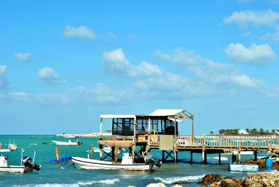 Fishing boats moored on sea against sky