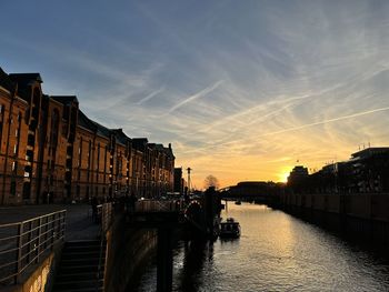 Canal amidst buildings against sky during sunset