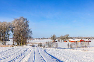 Snow covered field against clear blue sky