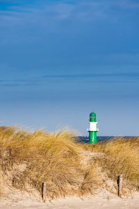 Lighthouse on beach against sky