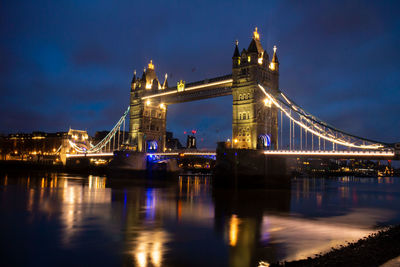 Illuminated bridge over river at night