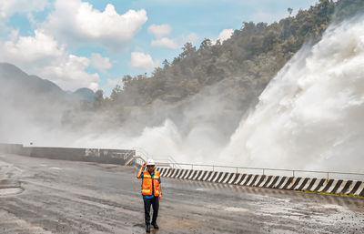 Rear view of man standing on mountain against sky