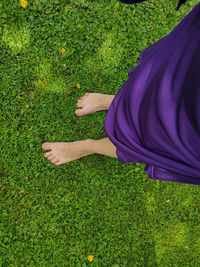 Low section of woman standing on field with bare feet