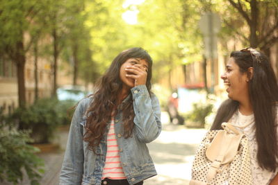 Two young woman laughing on city street