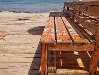 High angle view of wooden bench on pier at beach