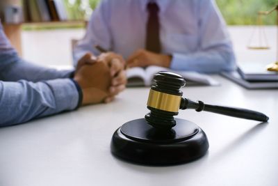 Lawyer and client having meeting with gavel on table in courtroom