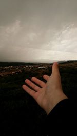 Close-up of hand against sea against sky