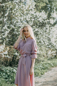 Blonde girl on a spring walk in the garden with cherry blossoms. female portrait, close-up. 