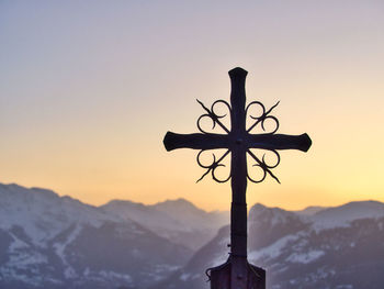 Silhouette cross against sky during sunset