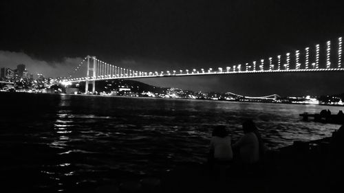 View of suspension bridge over river at night