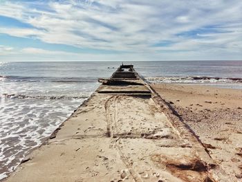 Pier over sea against cloudy sky